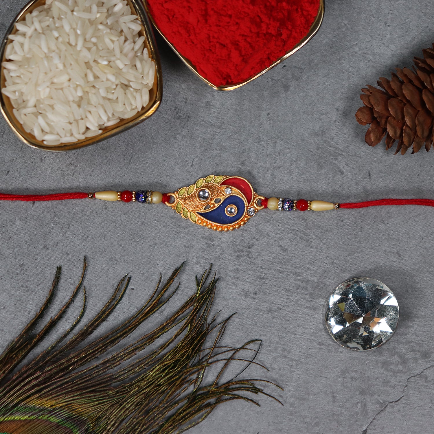 Elegant Rakhi With Enamel Paisley Design And Gold-tone Embellishments Elegant Rakhi With Enamel Paisley Design And Gold-tone Embellishments